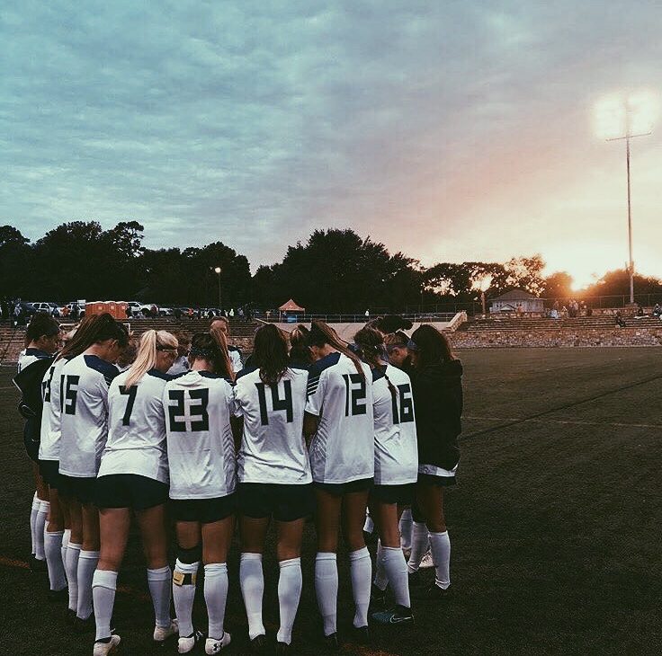 Team huddle at sunset under the stadium lights